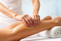 Eine Frau gönnt sich eine Massage der Waden.