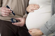 A man showing a pregnant woman a blood glucose monitor.