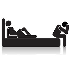 Schwarzweiß-Abbildung eines Bettes. Eine weibliche Figur liegt auf dem Bett und eine männliche Figur sitzt am Bettende und stützt den Kopf in seine Hände.