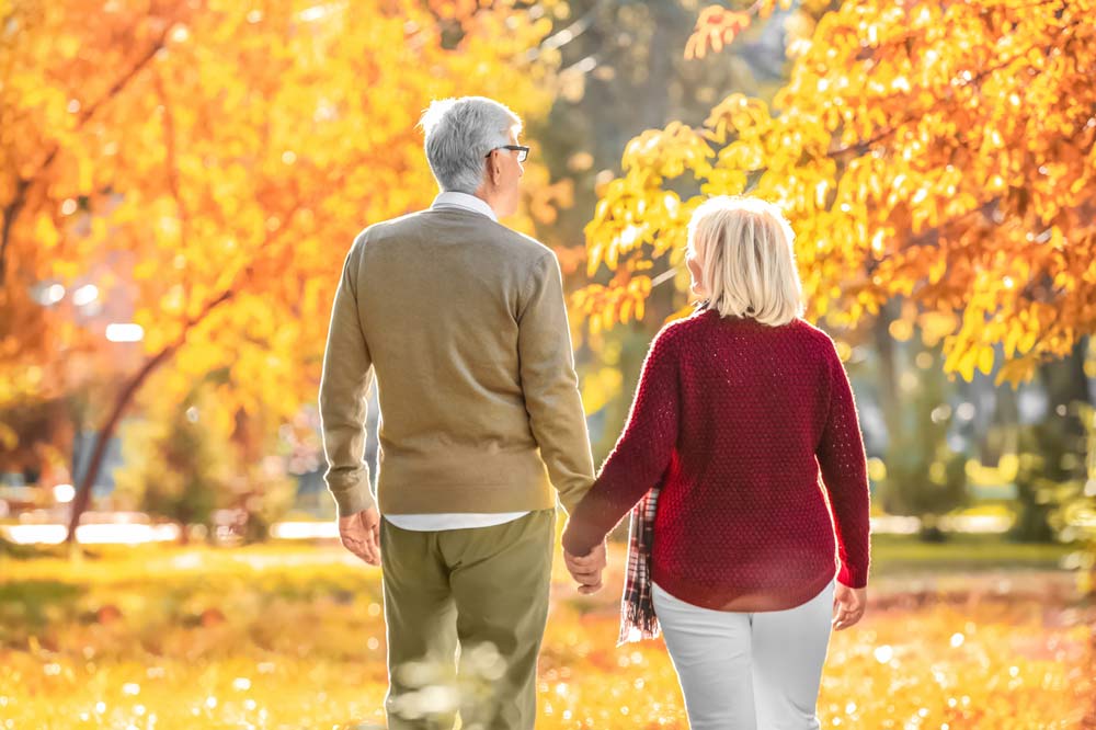 Ein älteres Paar spaziert durch einen herbstlichen Park.