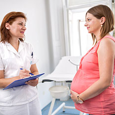 Jinekolog hamile bir kadına muayene sonuçlarını açıklıyor.