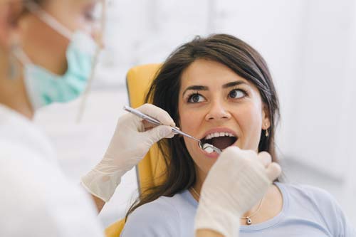 Dentystka zagląda do ust kobiety.