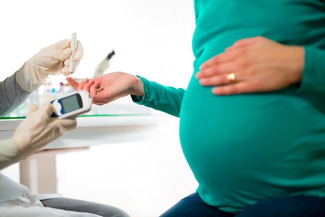 Einer schwangeren Frau wird der Blutzucker am Finger gemessen.