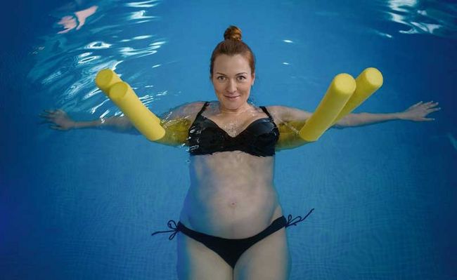 Eine schwangere Frau liegt in einem Pool 