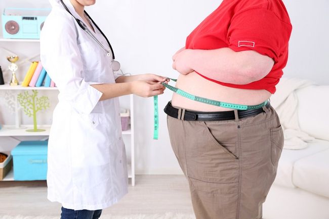 Ärztin misst Bauchumfang einer stark übergewichtigen Person mit einem Maßband 
