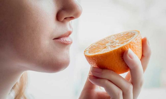 Eine Person riecht an einer Orange