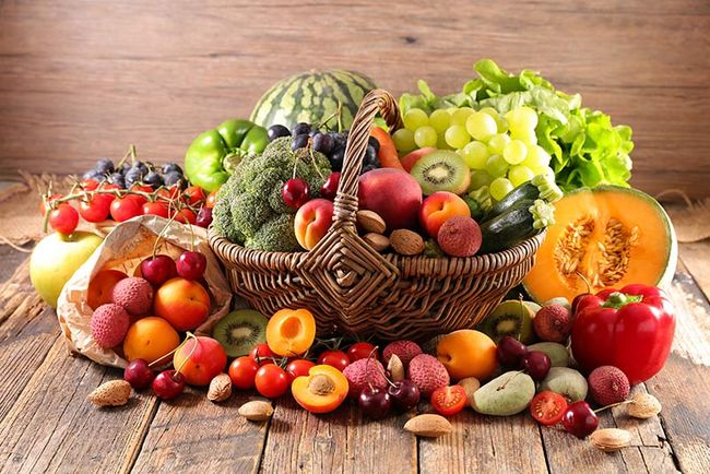 Auf einem Tisch steht ein Korb mit Obst und Gemüse.
