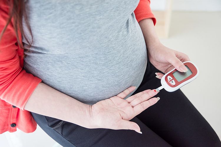 Eine schwangere Frau misst sich den Blutzucker.
