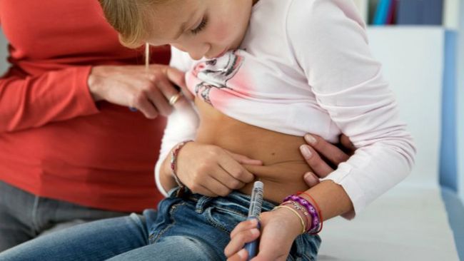Ein Mädchen mit Typ-1-Diabetes spritzt sich Insulin in ihre Bauchfalte.