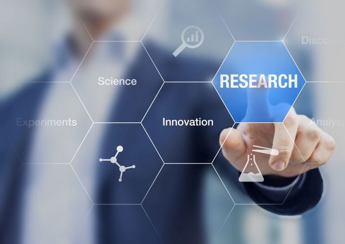 Eine Hand zeigt auf ein digitales Konzept mit verschiedenen Elementen wobei das Element "research" hervorgehoben ist.