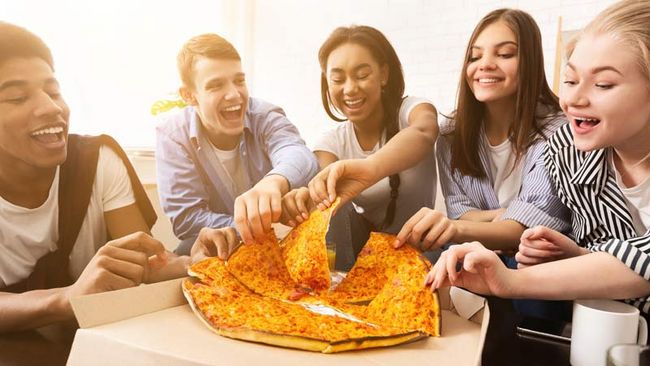 Eine Gruppe von 5 Jugendlichen beim Pizza essen.