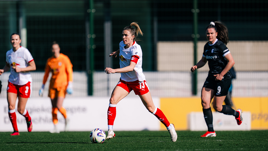 Sandra Starke rennt mit einem Ball auf dem Fußballplatz, hinter ihr sind andere Fußballspielerinnen zu sehen.