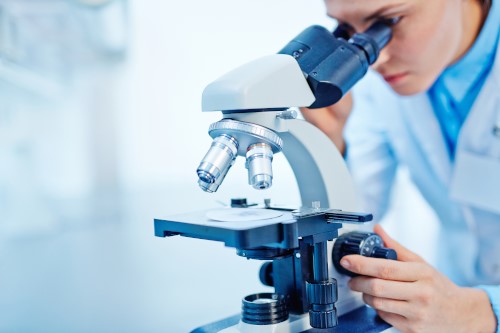 Frau im Labor schaut durch Mikroskop