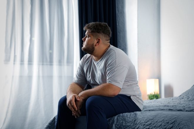 Ein Mann sitzt nachdenklich auf einem Bett