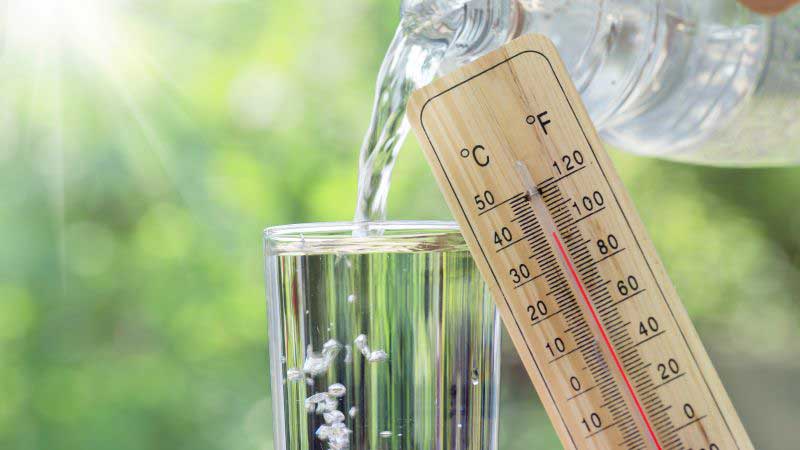 Ein Glas Wasser und ein Temperatur-Thermometer