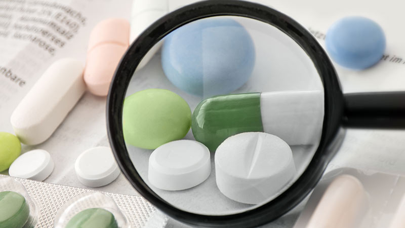 Blick durch eine Lupe auf mehrere verschiedene Tabletten.